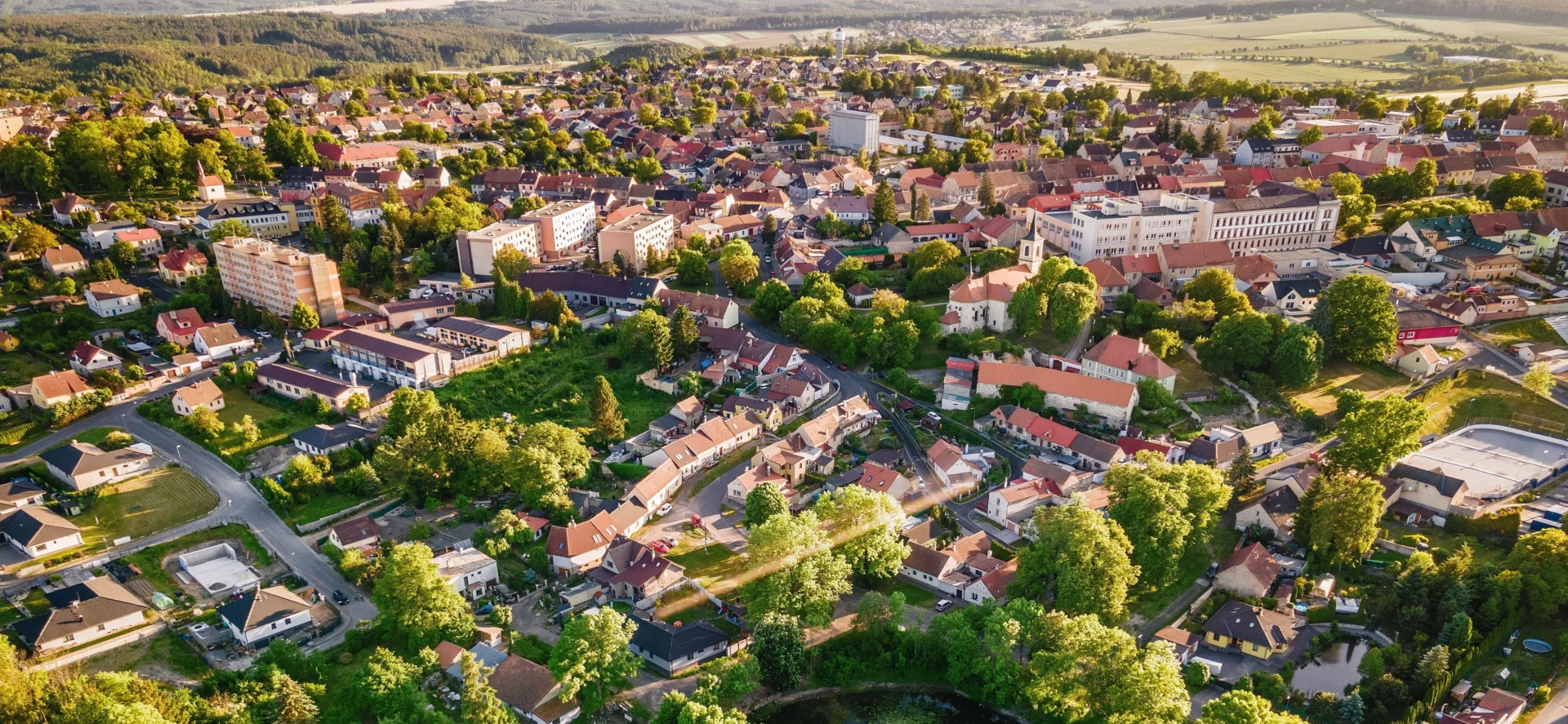 Panoramatický pohled na Nové Strašecí – město s bohatou historií a aktivní občanskou komunitou, obklopené zelení a zasazené do klidné krajiny středních Čech.
