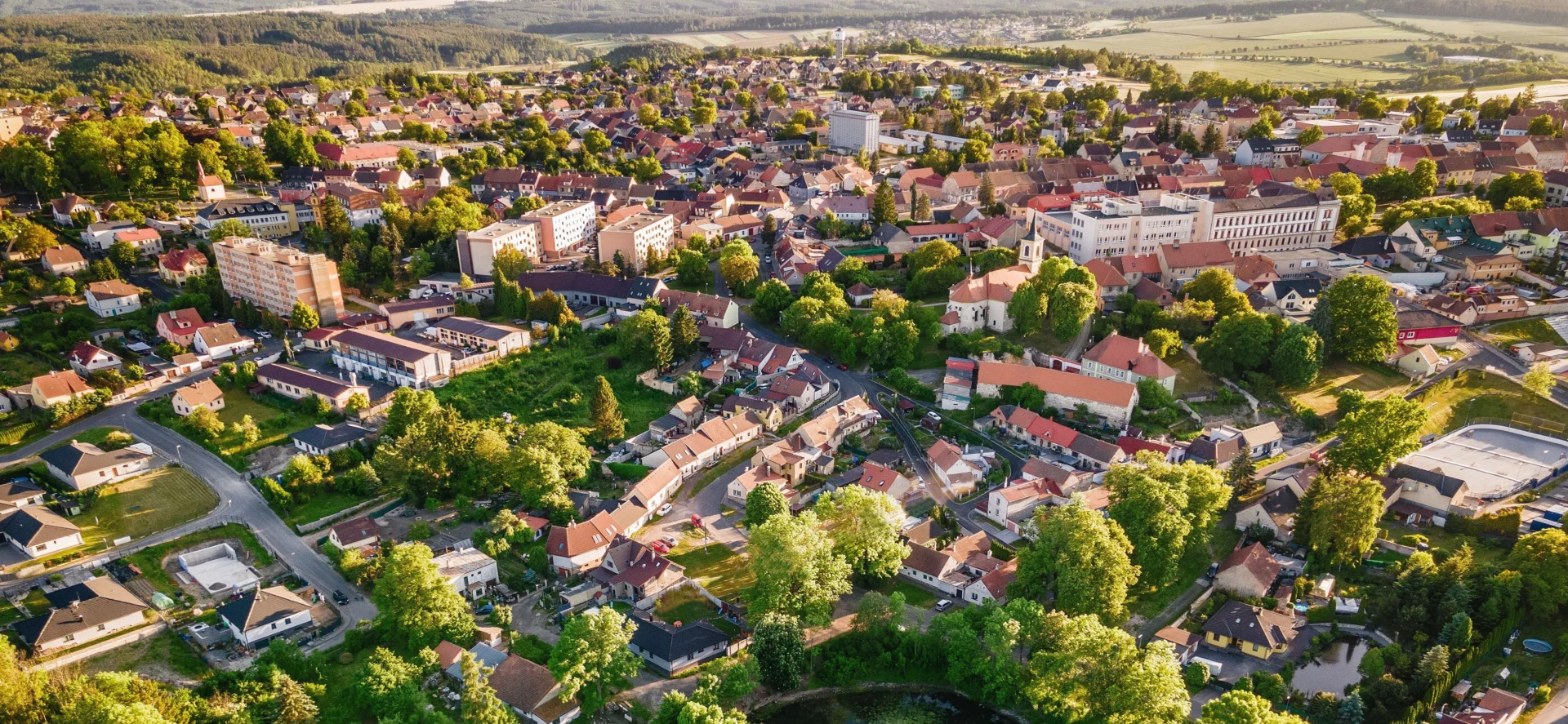 Panoramatický pohled na Nové Strašecí – město s bohatou historií a aktivní občanskou komunitou, obklopené zelení a zasazené do klidné krajiny středních Čech.
